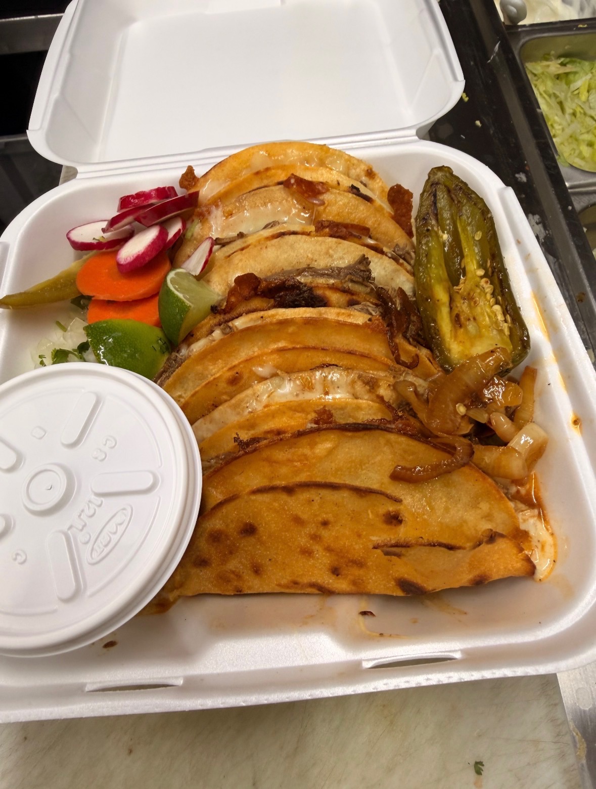 Quesabirria tacos packed to go with pickled vegetables and lime